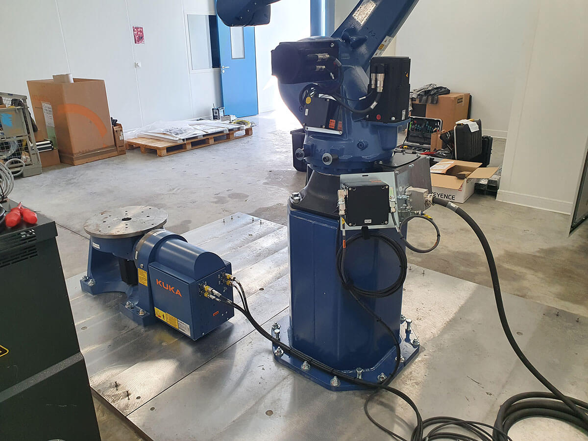 Průmyslový robot KUKA s rotačním polohovadlem pro automatizovanou výrobu.